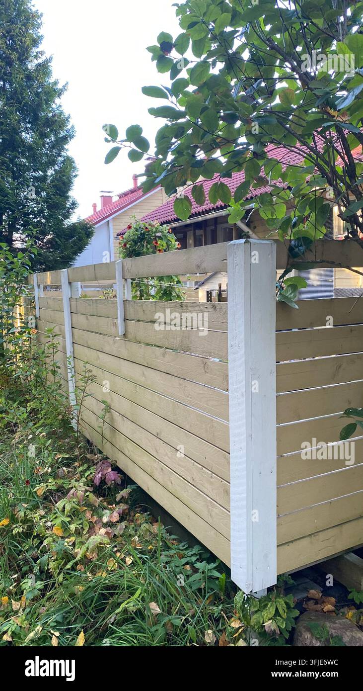 Clôture en bois brise-vue entourant une propriété résidentielle avec végétation de jardin Banque D'Images
