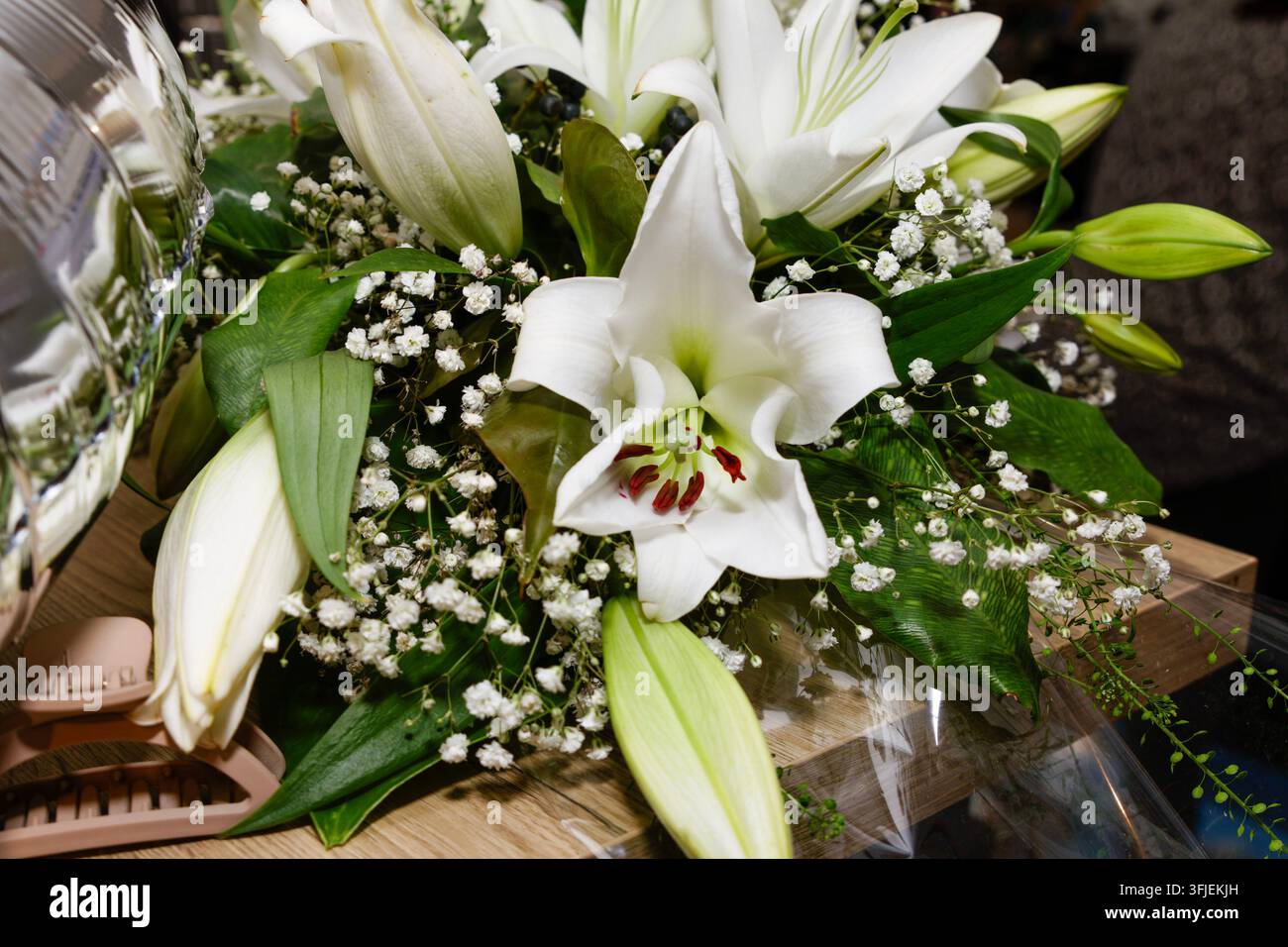 Lys blancs et fleurs de bougainvilléea arrangées en bouquet sur une surface en bois. Banque D'Images