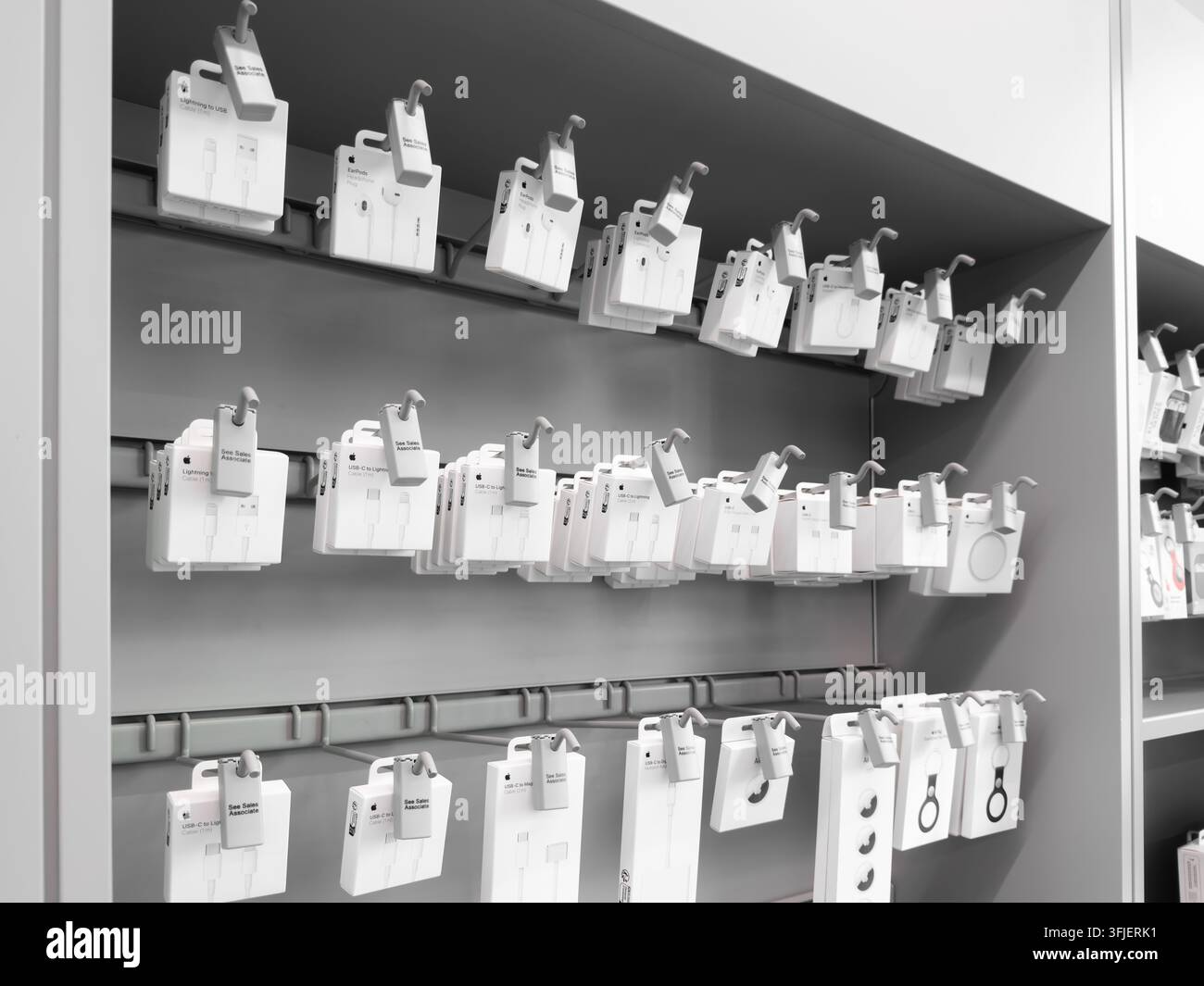 Poznań, Pologne - 19 septembre 2026 : Produits Apple disposés sur une étagère de vente au détail organisée avec des emballages blancs sur des crochets muraux reflétant un magasin moderne Banque D'Images