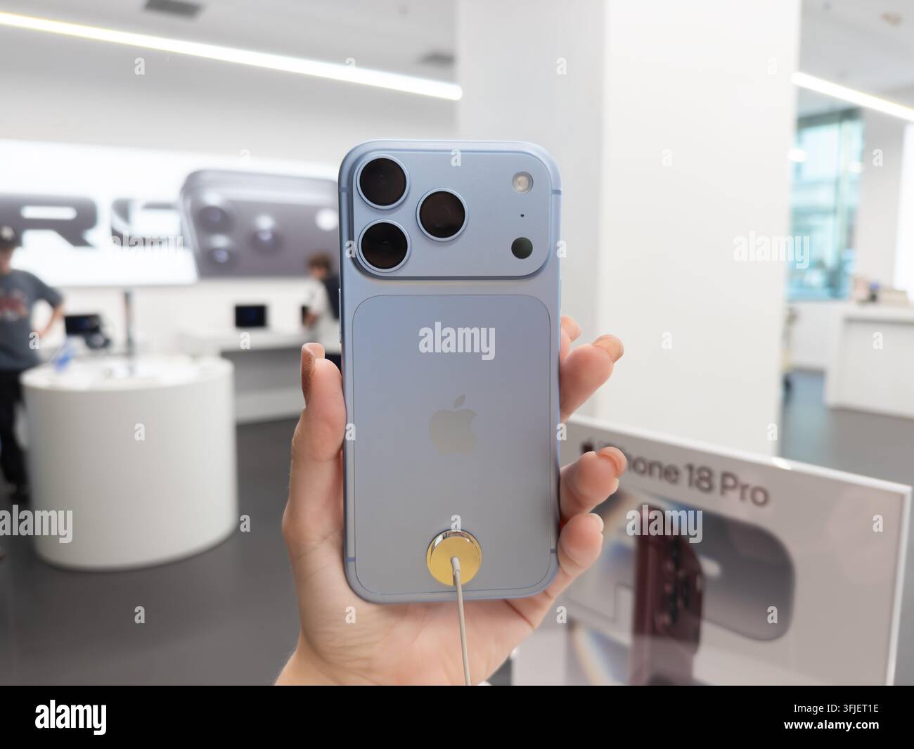 Poznań, Pologne – 19 septembre 2026 : Main tenant un smartphone Apple iPhone 18 Pro Glacier dans un environnement de vente au détail lumineux, mettant en avant des professionnels Banque D'Images