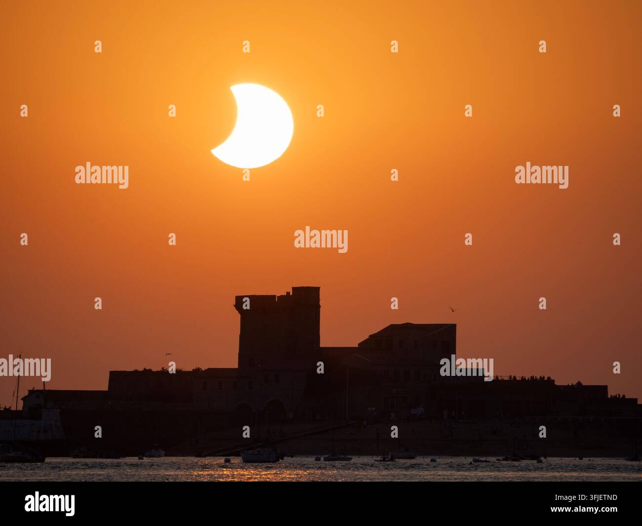 Coucher de soleil à la fin de l'éclipse solaire de 2026 pris sur la plage de Saint Jean de Luz avec la silhouette du Fort de Socoa Banque D'Images