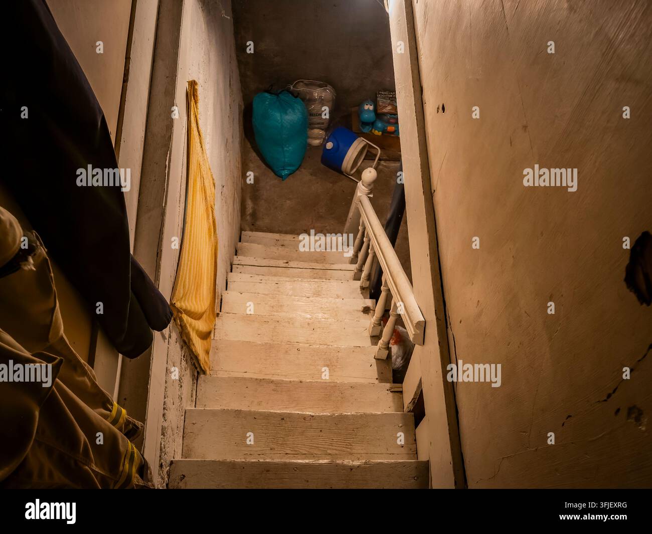 Regardant en bas des escaliers en bois abrupts menant à un espace de stockage sombre au sous-sol rempli d'anciens objets ménagers et de désordre Banque D'Images