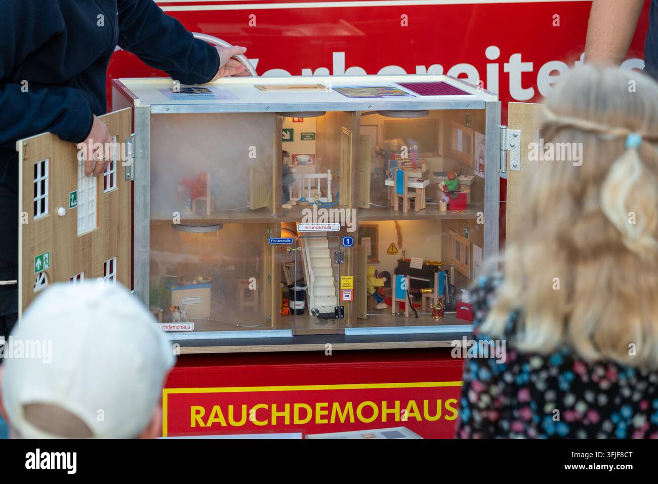 VIENNE, AUTRICHE, 12 septembre 2026 : Des enfants regardent une maison miniature de démonstration de fumée exposée lors d'un événement de sécurité intérieur. Banque D'Images