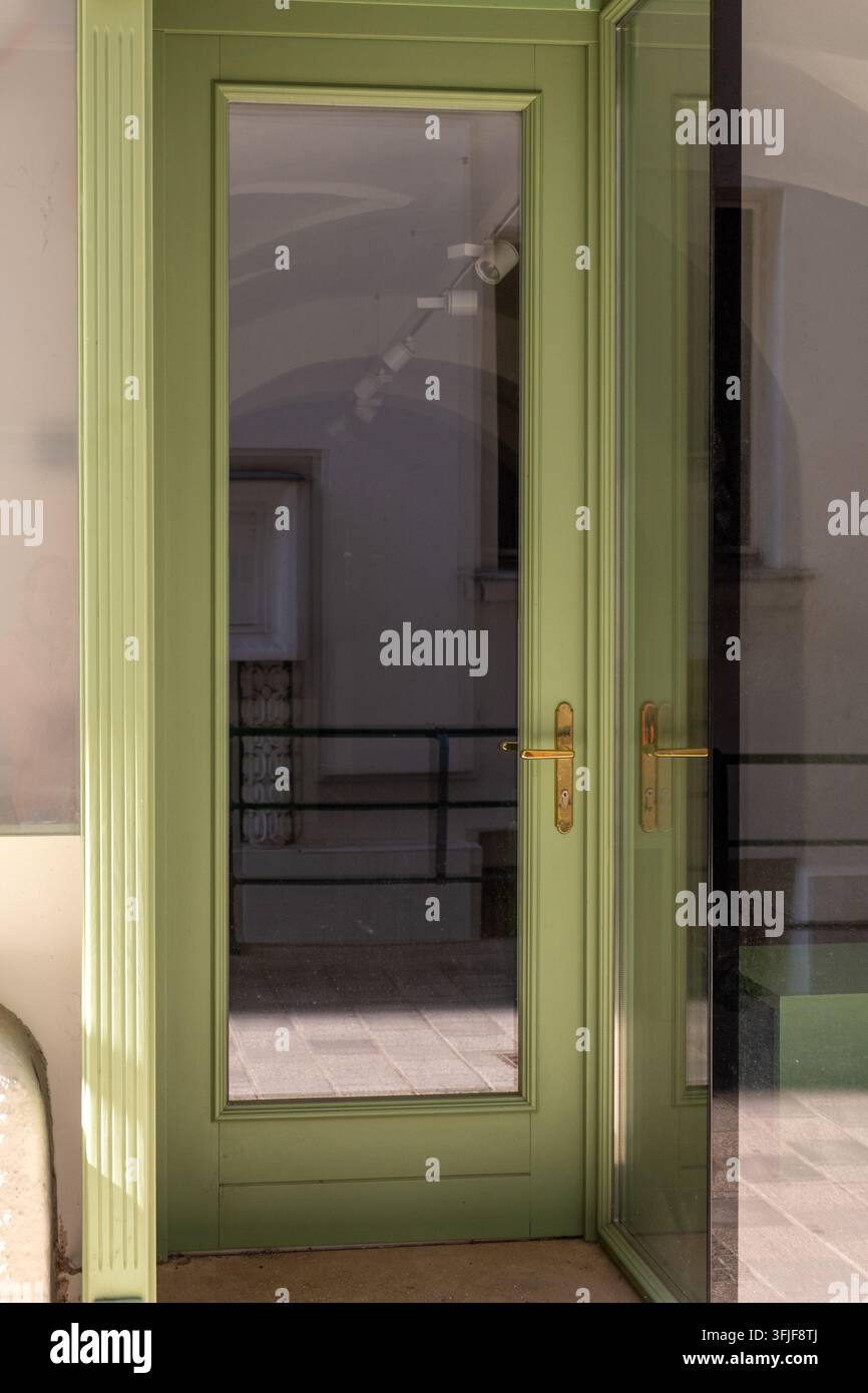 Des portes doubles en verre vert se dressent à l'entrée d'un intérieur de bâtiment calme. Banque D'Images