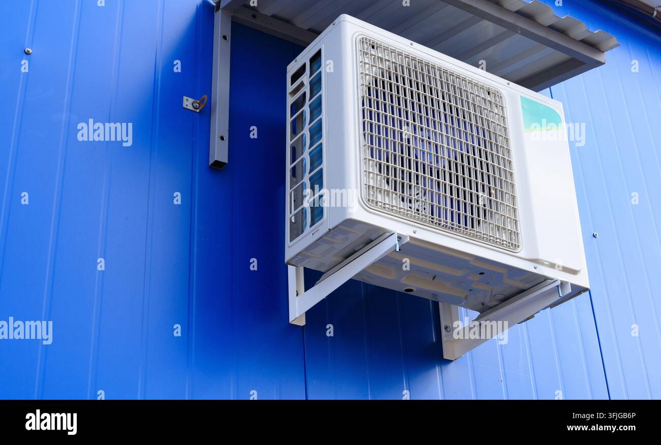 Unité de climatisation sur un mur de bâtiment. L'unité extérieure de climatisation est montée sur un mur bleu. Unité extérieure d'une climatisation et de ventilation Banque D'Images