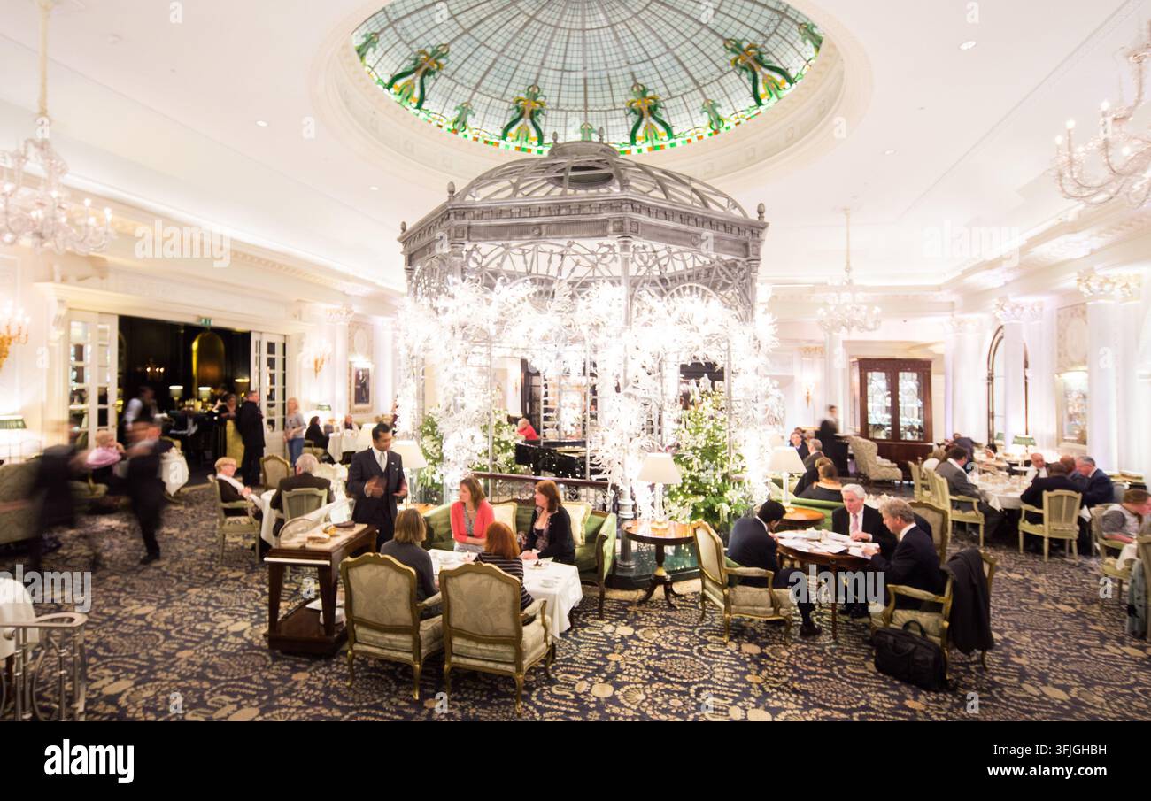 Les invités profitent du thé de l'après-midi sous le dôme de verre emblématique et le gazebo dans le Thames Foyer du Savoy Hotel, à Londres. Banque D'Images