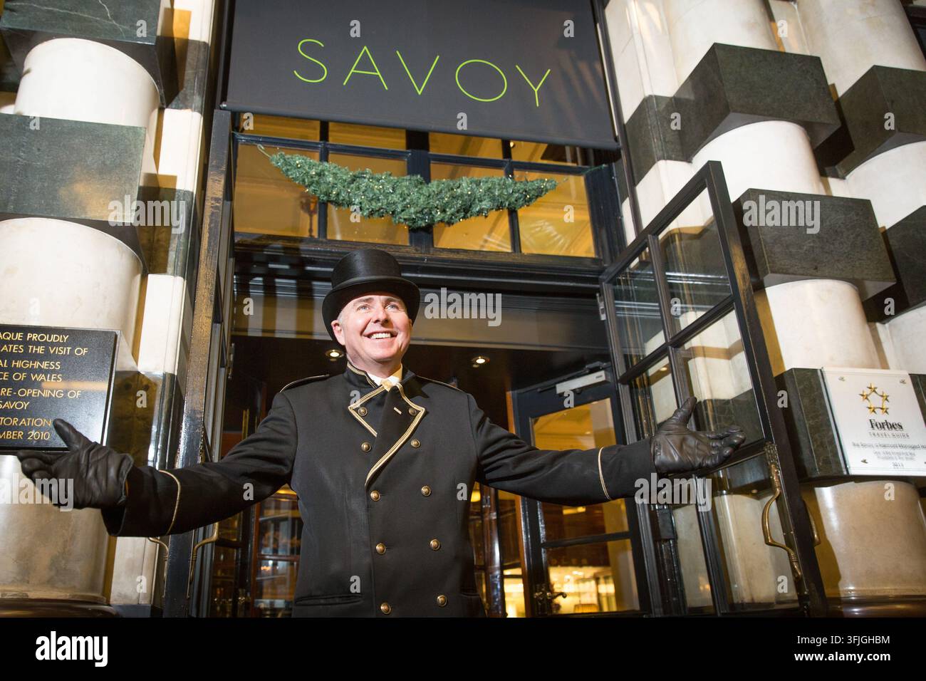 Un portier souriant au Savoy Hotel historique de Londres accueille les visiteurs, célébrant la grande réouverture du monument emblématique en 2010. Banque D'Images
