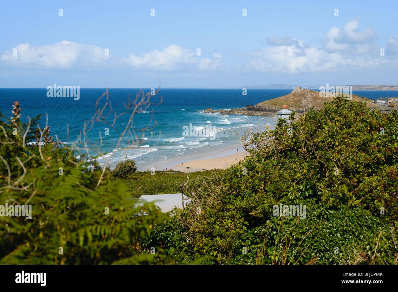 Vue élevée sur une plage de sable, des vagues douces et une pointe rocheuse à Saint Ives, Cornwall, Angleterre sous un ciel bleu et des nuages dérissants. Banque D'Images