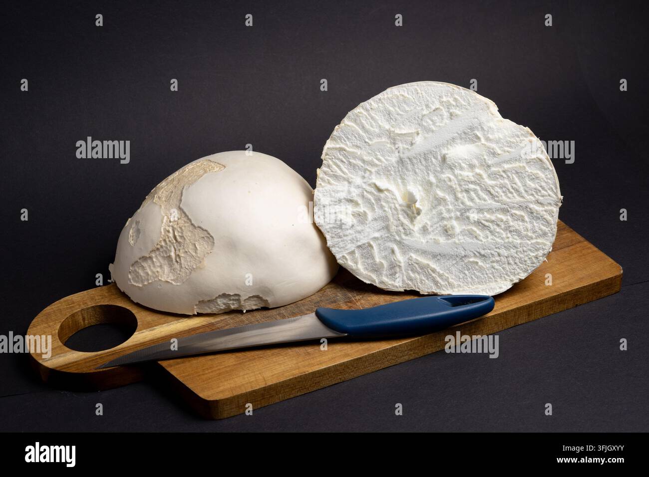 Champignon géant coupé en deux sur une planche à découper en bois avec un couteau Banque D'Images
