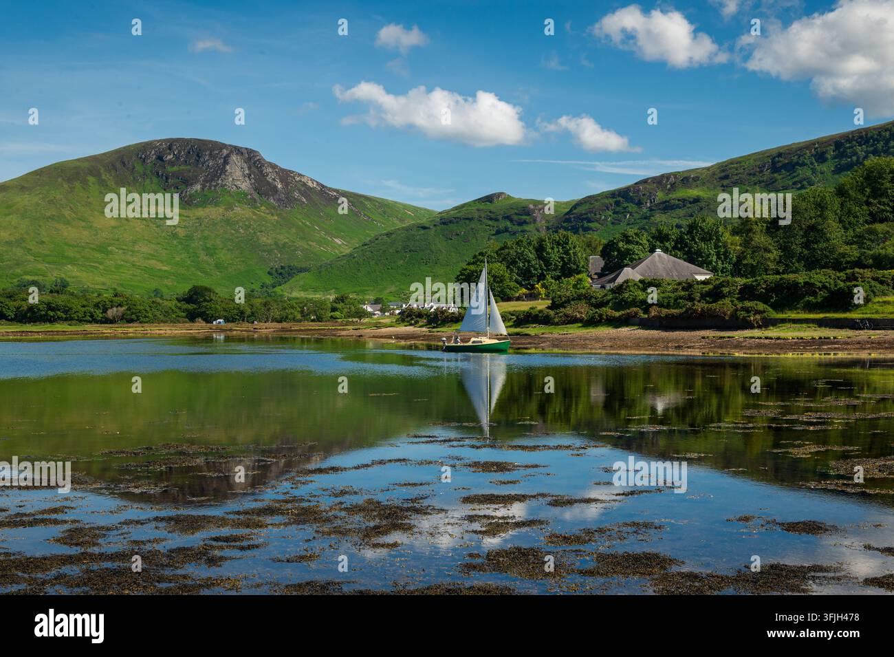 Bateau à voile dans les eaux de la baie de Lochranza, avec un joli reflet, Île d'Arran, Écosse Banque D'Images