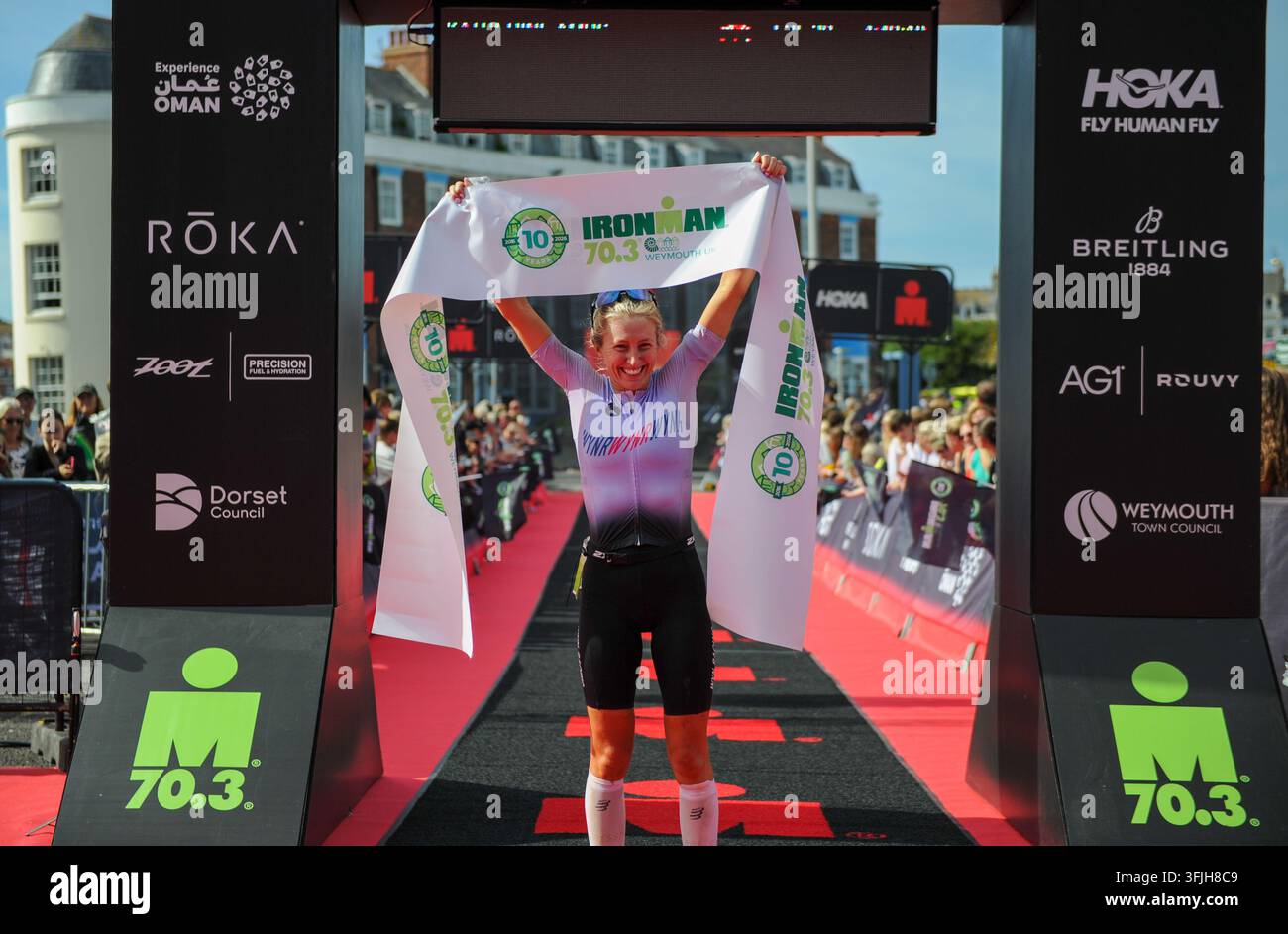 Weymouth, Dorset, Royaume-Uni. 20 sep., 2026. Katherine Amps (112) franchit la ligne d’arrivée pour remporter la course féminine de l’IRONMAN 70.3 Weymouth en un temps de 4 h 49 min 10 s. Crédit : David Partridge/Alamy Live News Banque D'Images