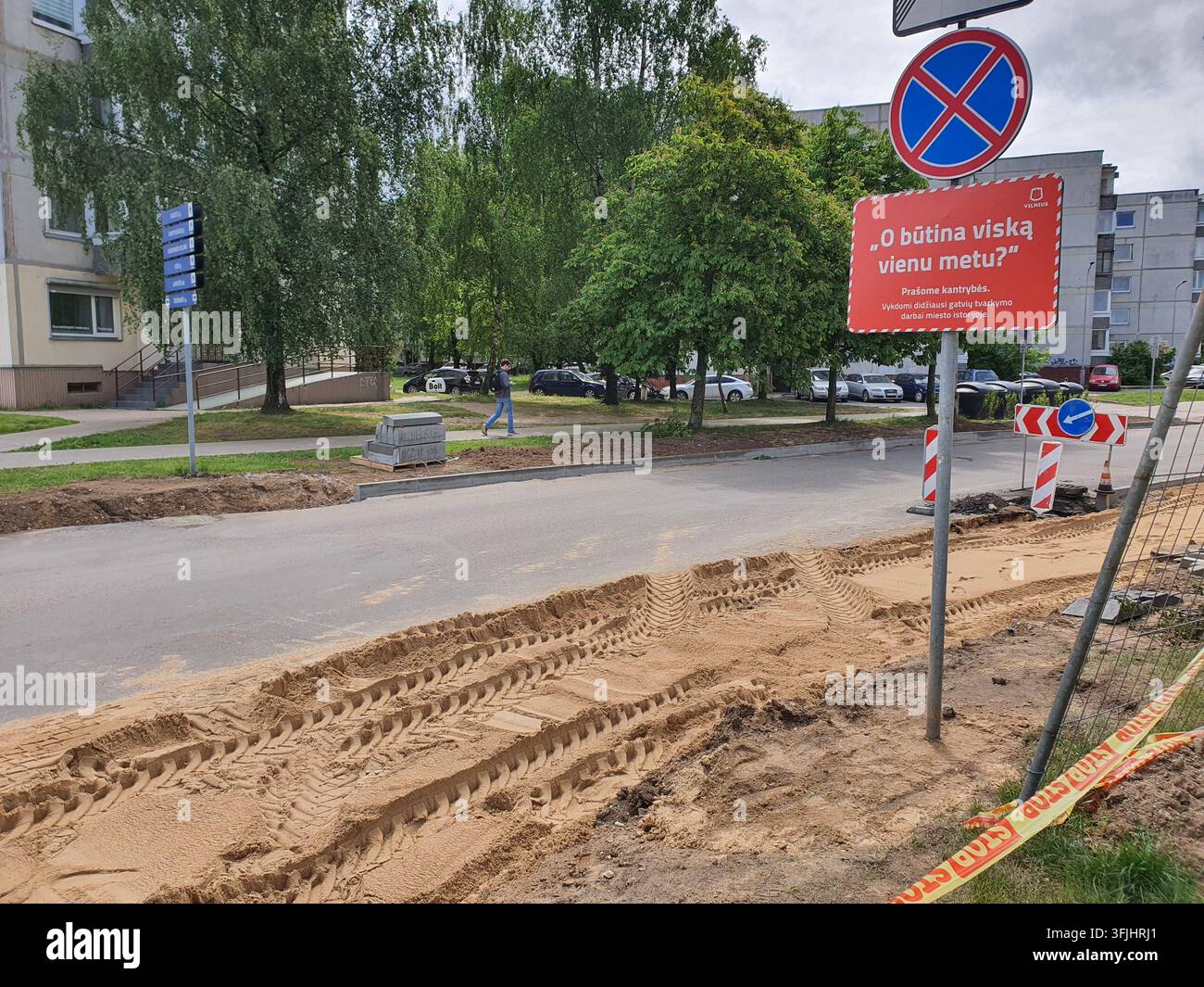 Un chantier de rénovation de rue dans un quartier résidentiel avec du sable creusé et des traces de pneus de machines lourdes visibles au premier plan. A Banque D'Images