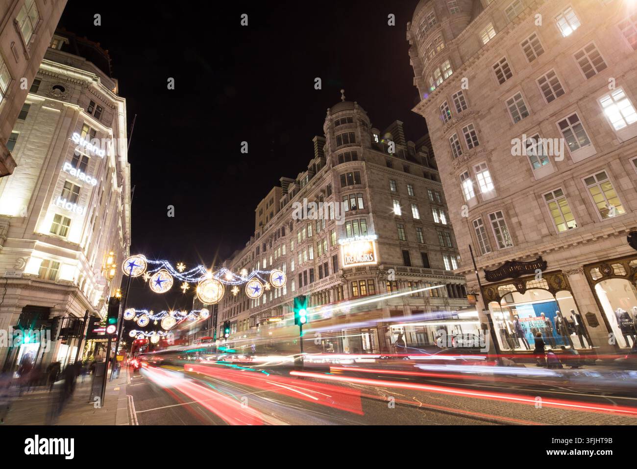 Les lumières de Noël illuminent le Strand Palace Hotel et Exeter Street à Londres pour les fêtes, tandis que la circulation du soir file à toute vitesse. Banque D'Images