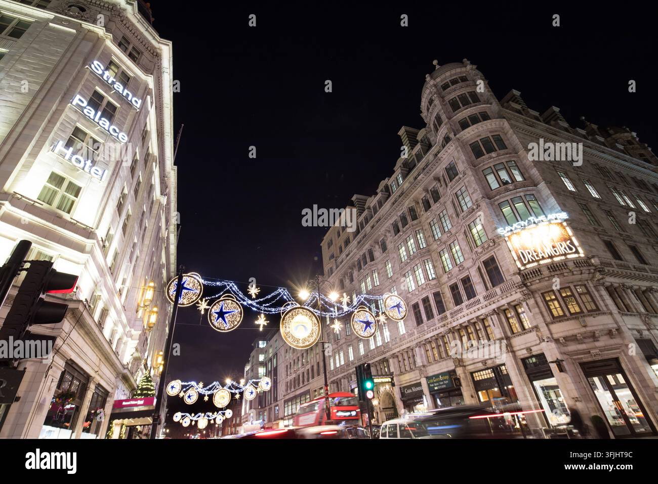 Les lumières festives illuminent le Strand de Londres, projetant une lueur de fêtes sur le Strand Palace Hotel et le Savoy Theatre lors d'une nuit animée. Banque D'Images