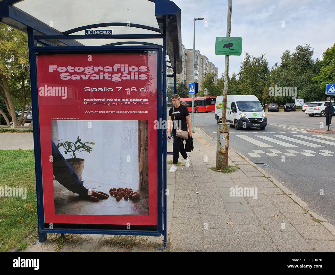 Un abri de bus avec une affiche publicitaire rouge se dresse sur un trottoir à Vilnius, en Lituanie. L'affiche fait la promotion de "Fotografijos Savaitgalis" Banque D'Images