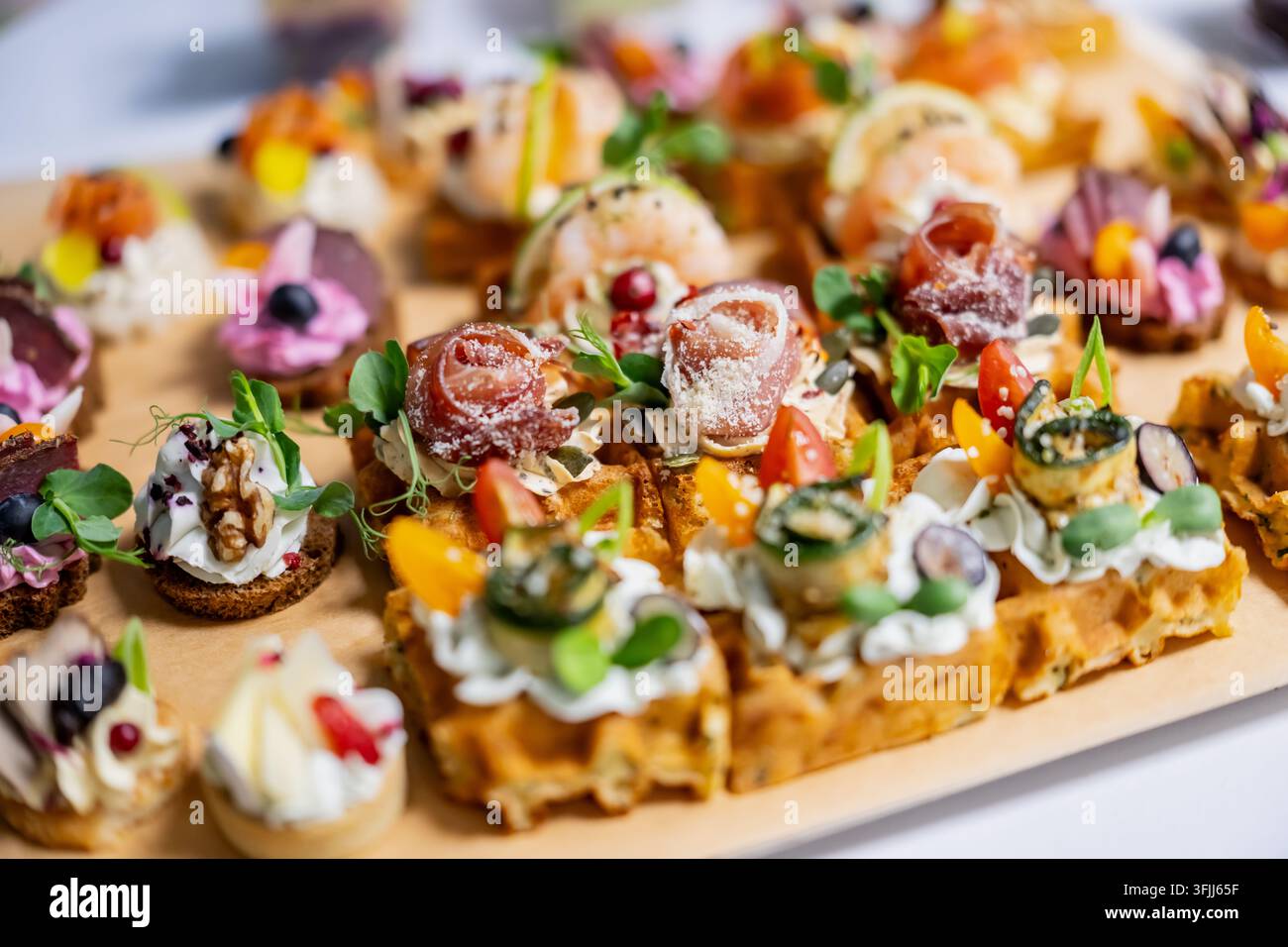 Canapés gaufrés savoureux garnis de viande séchée roulée, de fromage doux et de légumes, disposés avec divers morceaux de pain pour réceptions traitées et appetiz Banque D'Images