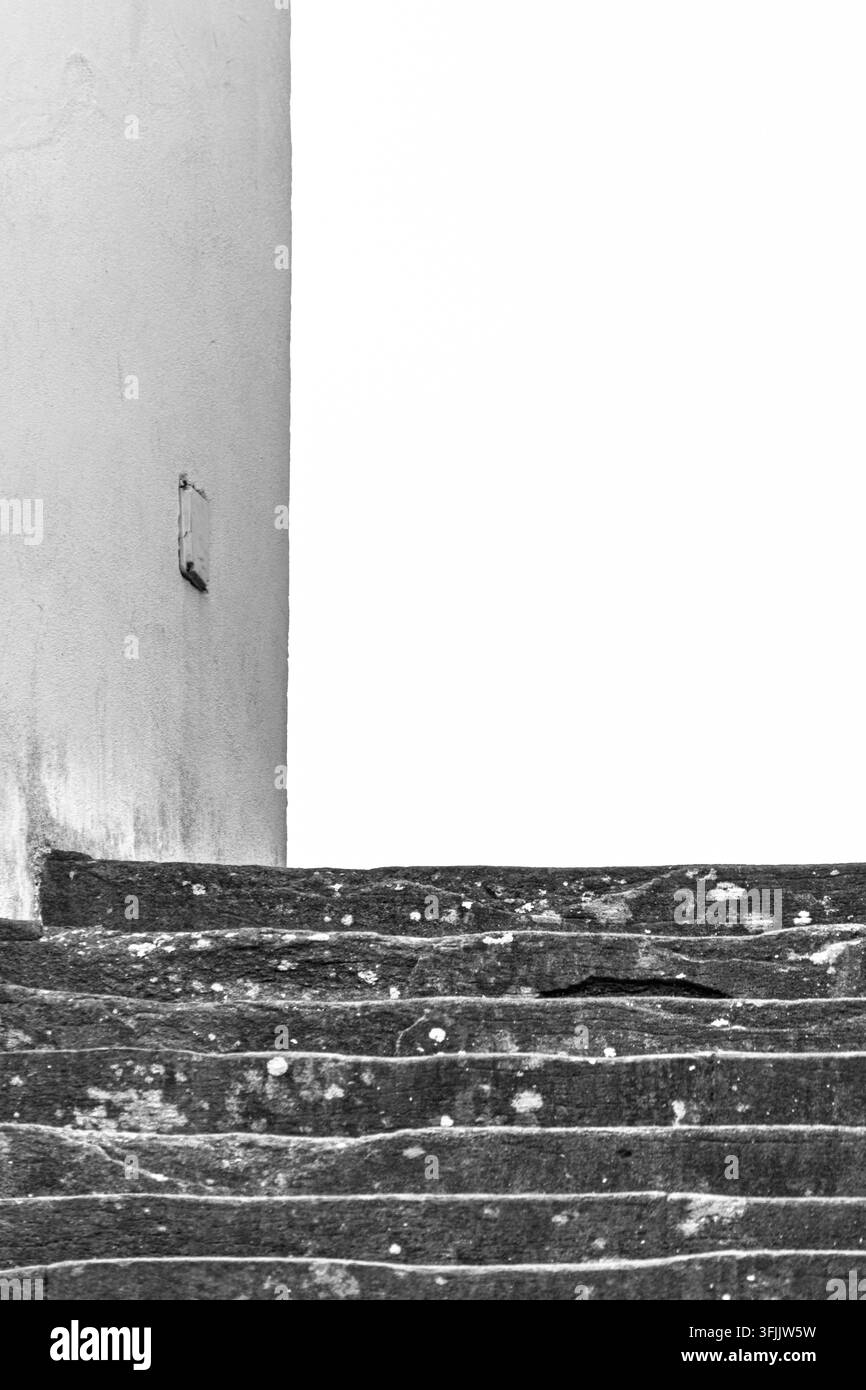 Composition minimaliste en noir et blanc d'escaliers en pierre usée contre un ciel d'un blanc pur Banque D'Images