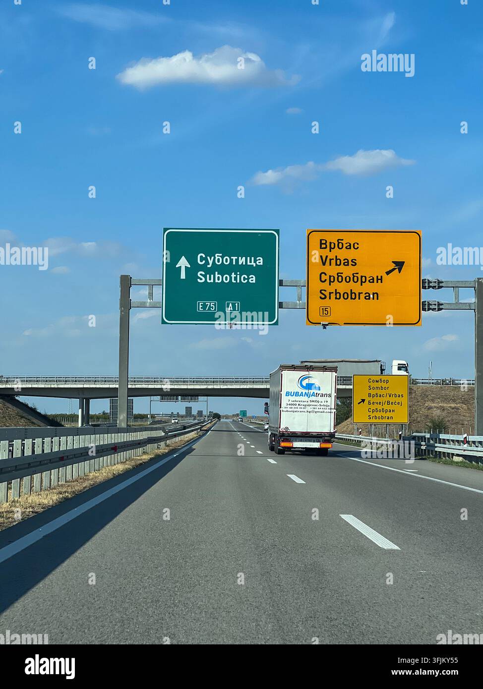 Panneaux de signalisation surélevés sur l'autoroute A1/E75 en direction de Subotica, avec un camion et la sortie pour Vrbas et Srbobran sous un ciel bleu en Voïvodine, Serbie - Image de stock capturée avec un smartphone