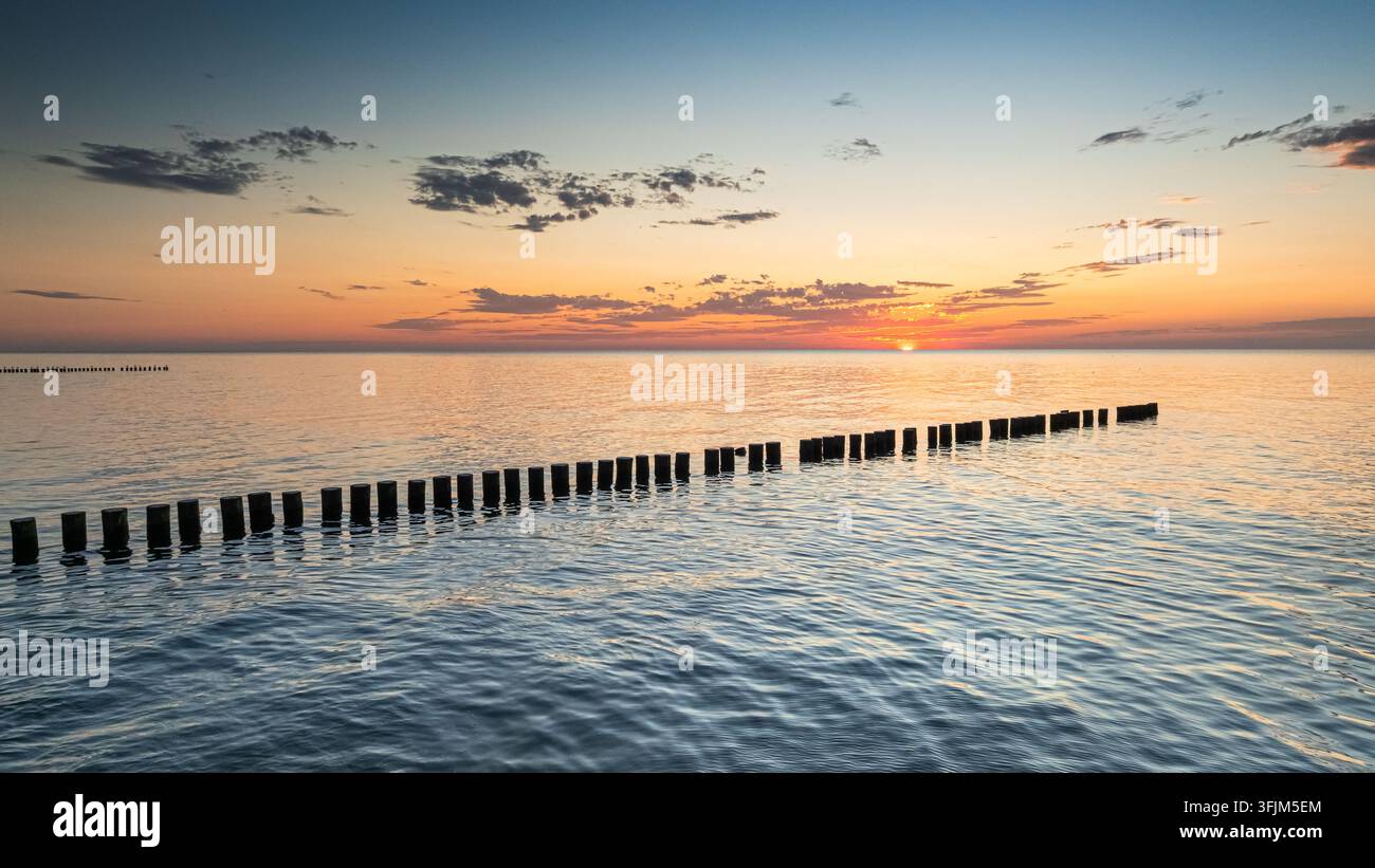 Brise-lames de la mer Baltique brillant sous un coucher de soleil calme en Pologne en été. Vue aérienne de la mer Baltique après une tempête. Banque D'Images