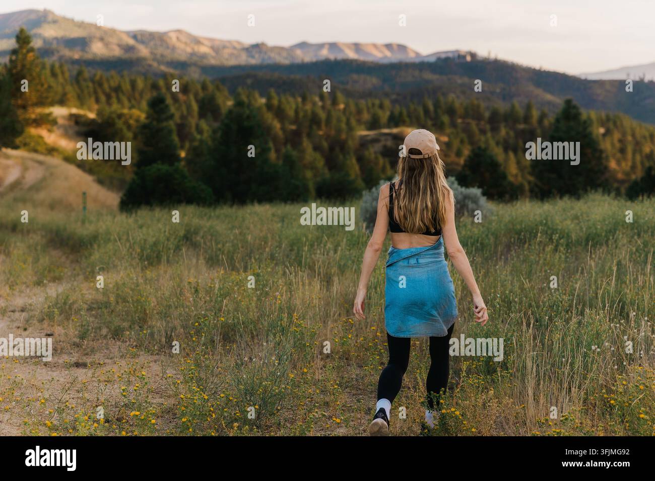 Femme marchant sur un sentier naturel à travers un paysage montagneux Banque D'Images