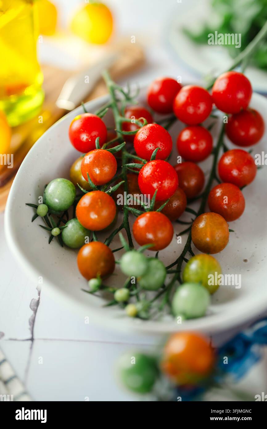 Tomates cerises rouge et vert vibrantes sur la vigne dans un bol Banque D'Images