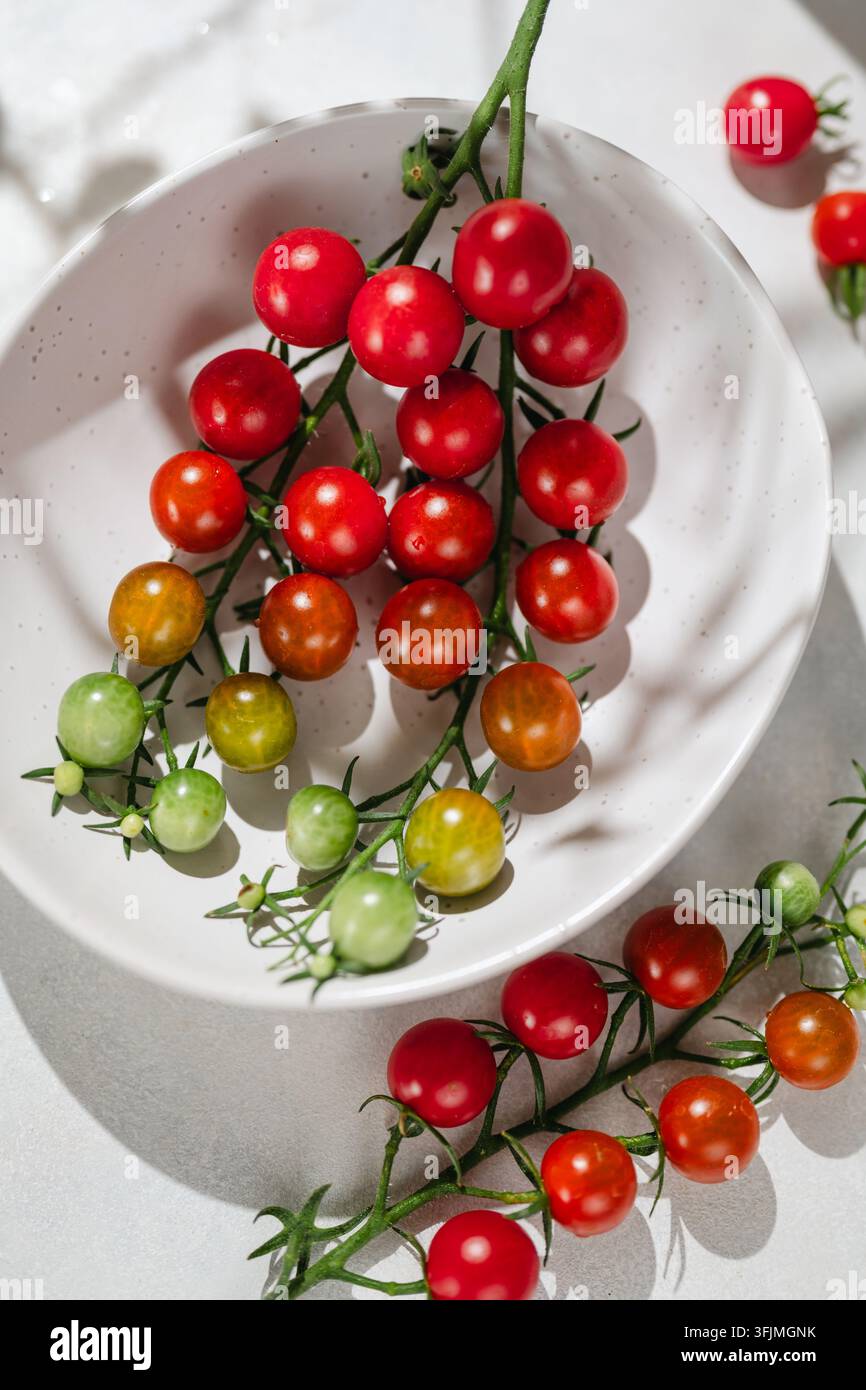 Tomates cerises mûrissant sur la vigne dans un bol blanc Banque D'Images