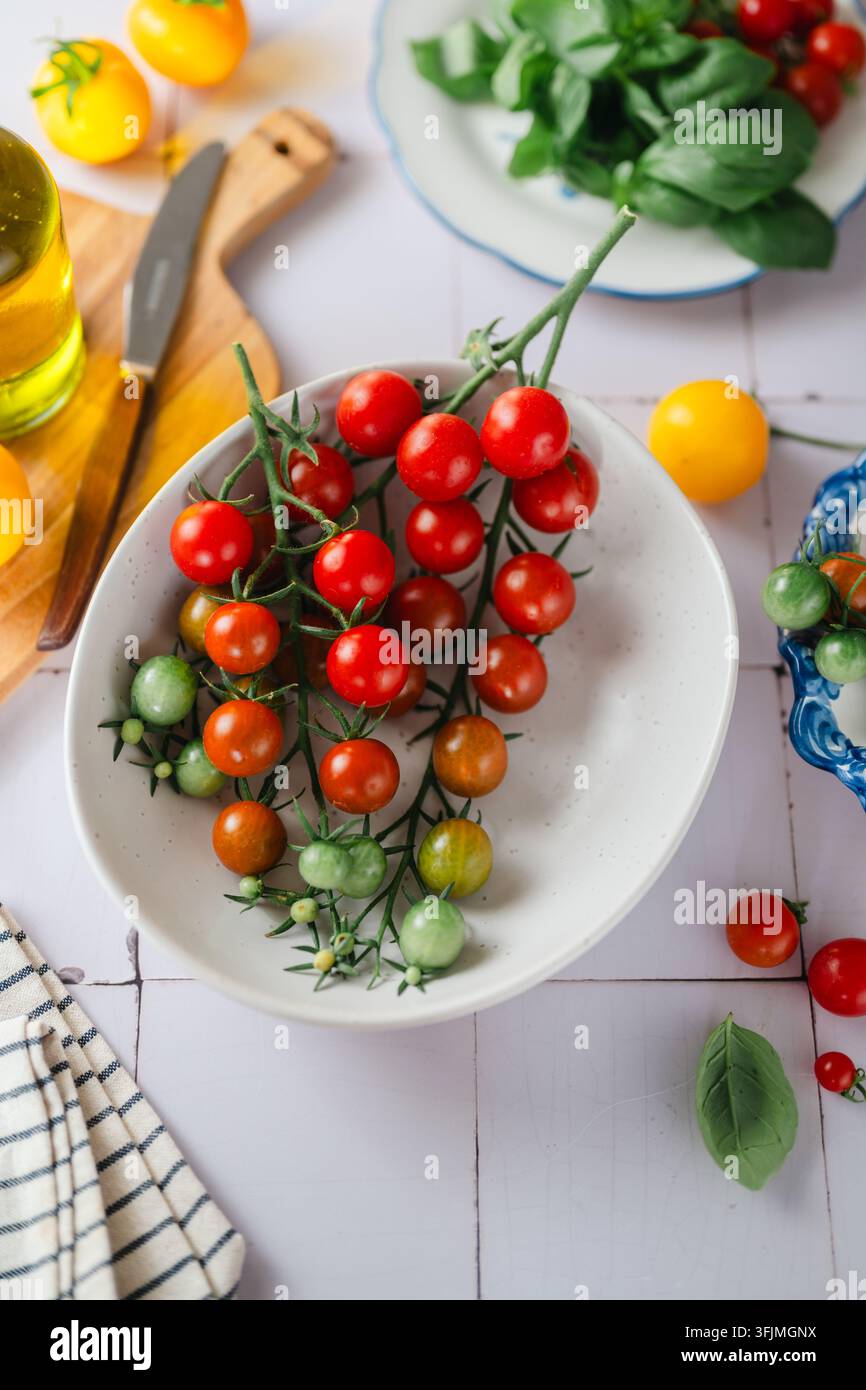 Tomates cerises rouges et vertes fraîches sur la vigne Banque D'Images