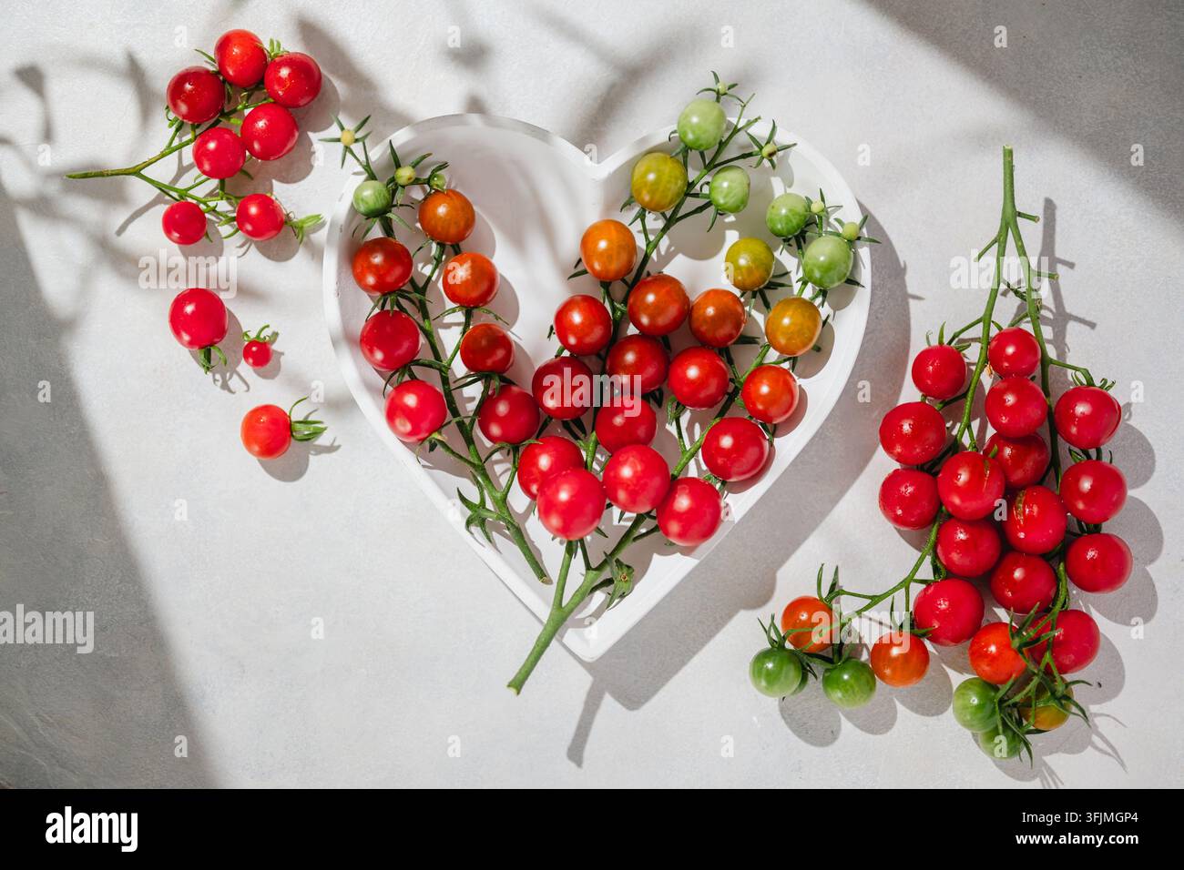 Tomates cerises sur la vigne dans un bol en forme de cœur Banque D'Images