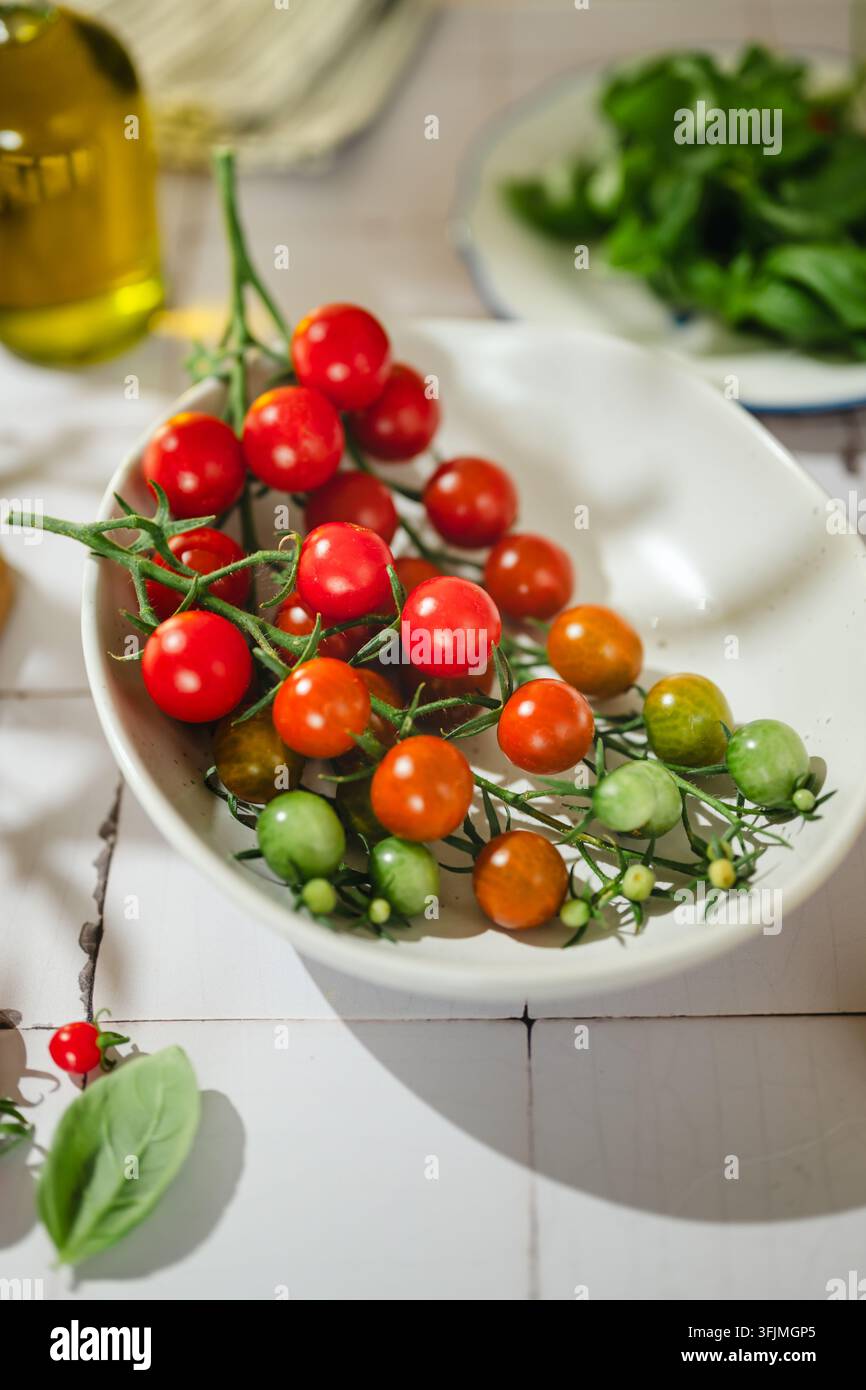 Des tomates cerises fraîches mûrissant sur la vigne dans un bol blanc Banque D'Images