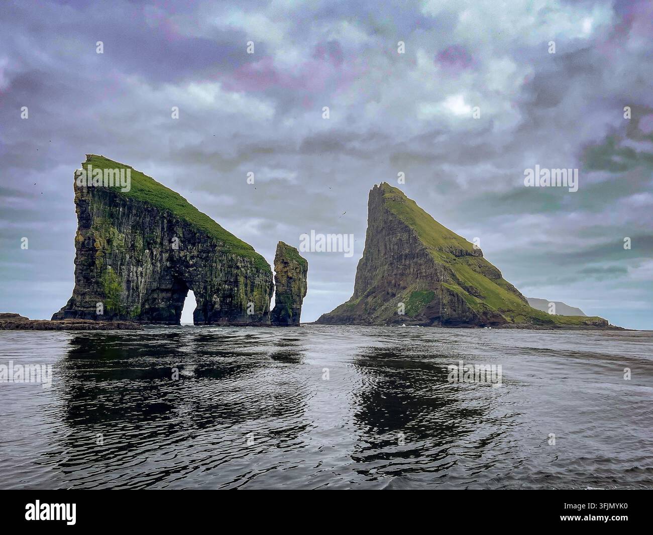 Falaises connues sous le nom de Drangarnir avec une grande arche naturelle située entre l'île de Vagar et l'îlot de Tindholmur dans les îles Féroé. Banque D'Images