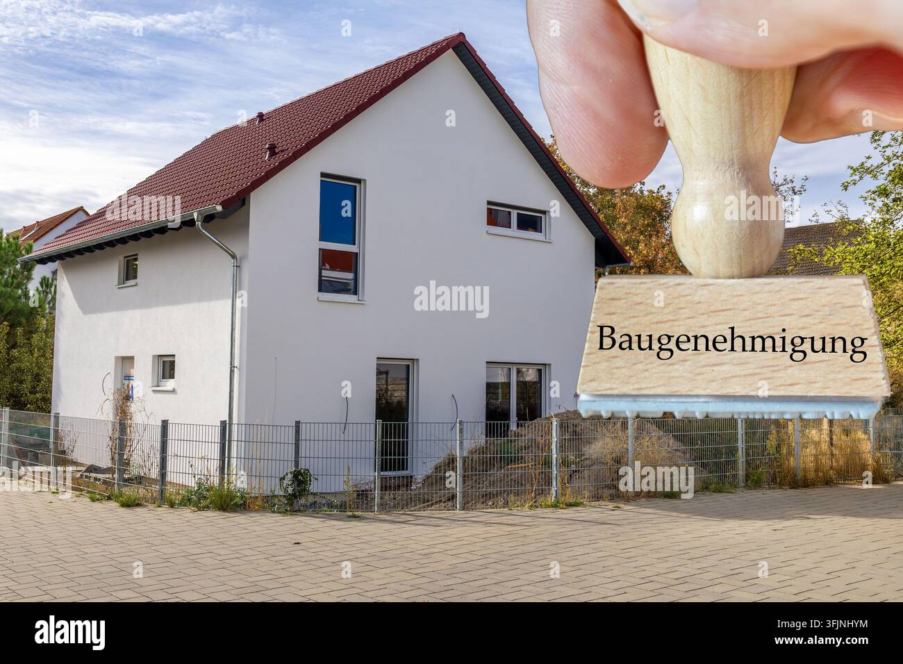 (Photomontage) Un timbre portant les mots BAUGENEHMIGUNG (permis de construire) devant une maison individuelle presque terminée Banque D'Images