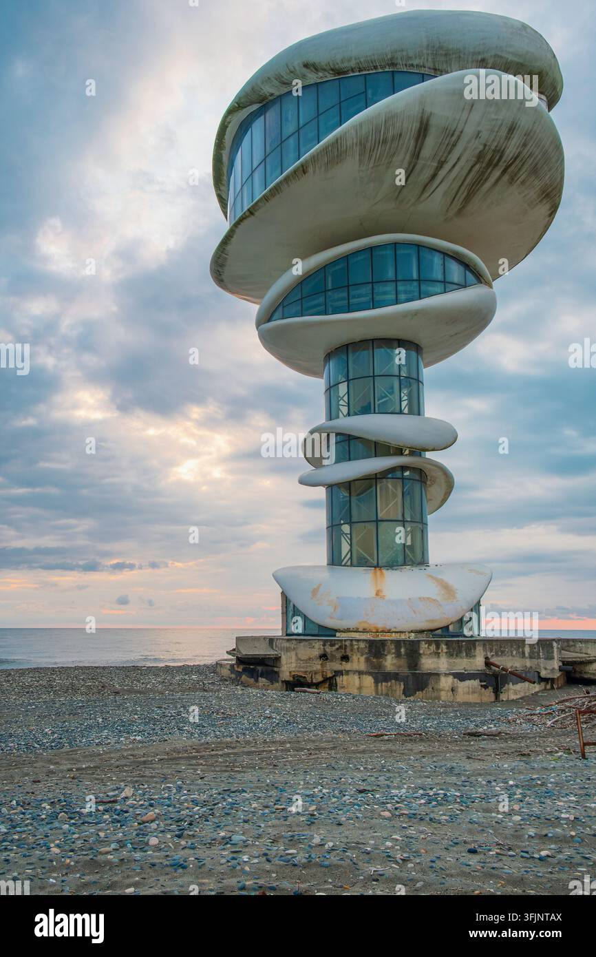 Tour moderne érodée aux formes de béton courbes et façade vitrée sur la côte de la mer Noire dans la station balnéaire d'Anaklia, Géorgie. Détérioration architecturale Banque D'Images