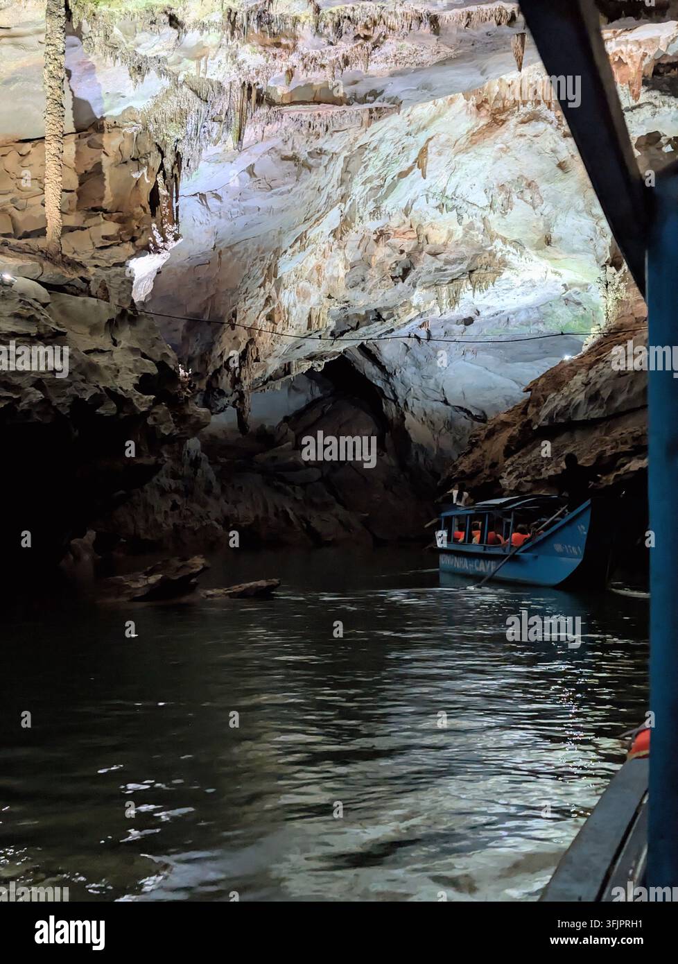 PHONG NHA, VIETNAM - 18 MARS 2026 : Bateau touristique bleu marqué PHONG NHA CAVE naviguant à travers la caverne brillamment éclairée remplie de stalactites suspendues - Image de stock capturée avec un smartphone