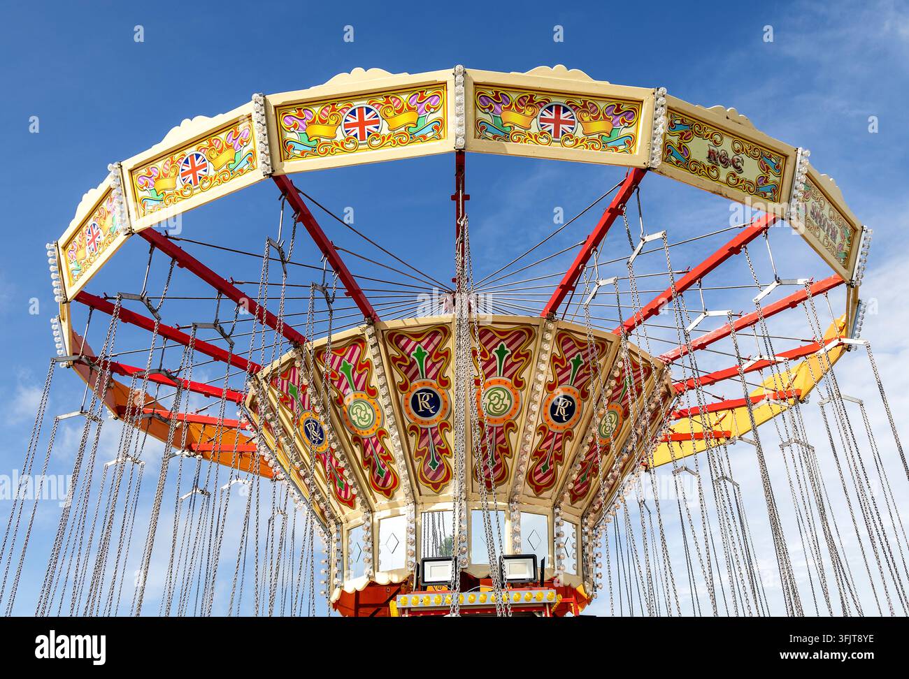 Manège de fête foraine peint de manière vive contre un ciel d'été bleu évoquant l'excitation amusante et les jours d'été insouciants Banque D'Images