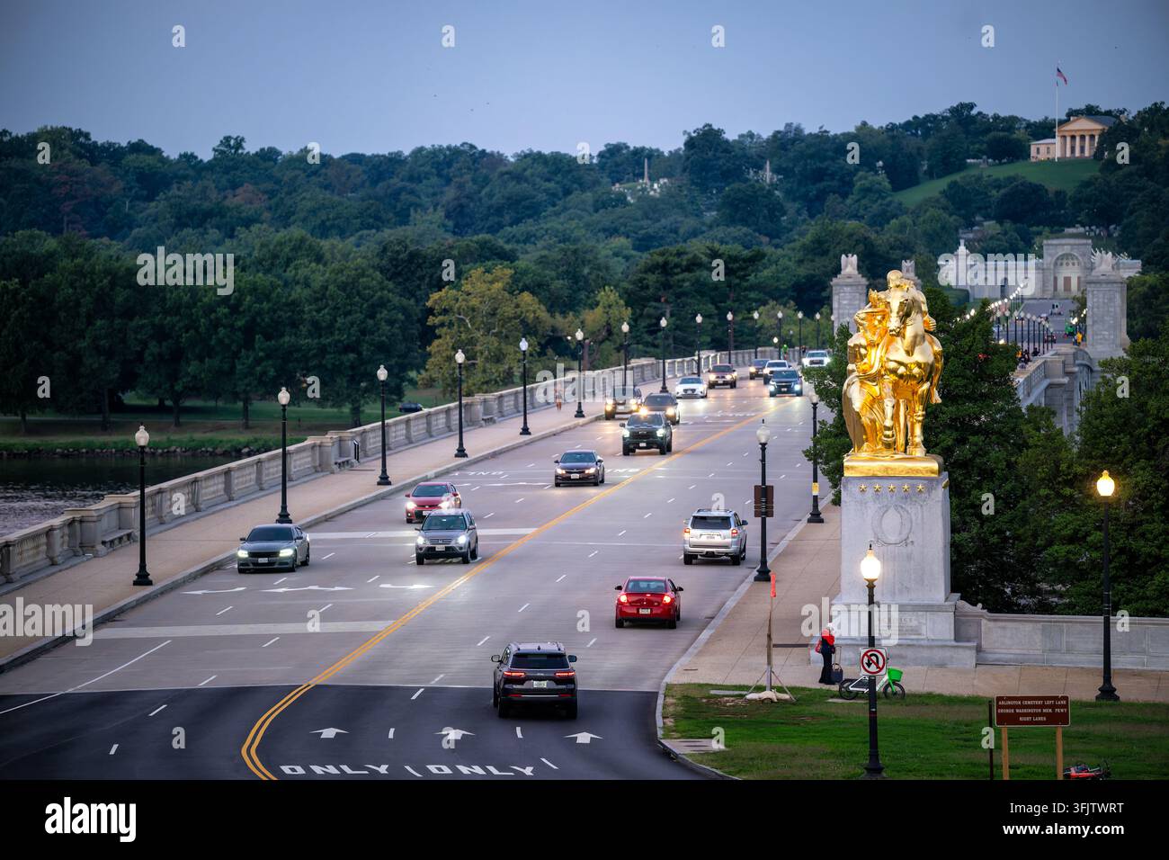 Statue du Sacrifice au-dessus du pont commémoratif d'Arlington à l'aube | WASHINGTON — La statue dorée du Sacrifice surplombe le pont commémoratif d'Arlington et les portes du cimetière national d'Arlington à l'aube, jeudi 17 septembre 2026. Coulée à Florence en 1950 dans le cadre du cadeau d'après-guerre de l'Italie aux États-Unis, la bronze a été dorée au mercure par des artisans italiens utilisant une ancienne technique romaine interdite de longue date dans le pays. La maison Arlington couronne la colline au-delà, marquant le manoir que Robert E. Lee quitta pour la dernière fois en avril 1861. Le pont, conçu par McKim, Mead et White et achevé en 1932, porte Banque D'Images