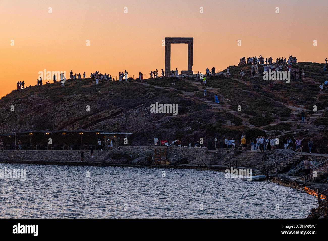 Naxos, Grèce – 1er juin 2026 : Portique du temple d’Apollon sur une colline au coucher du soleil à Naxos avec des foules de visiteurs Banque D'Images