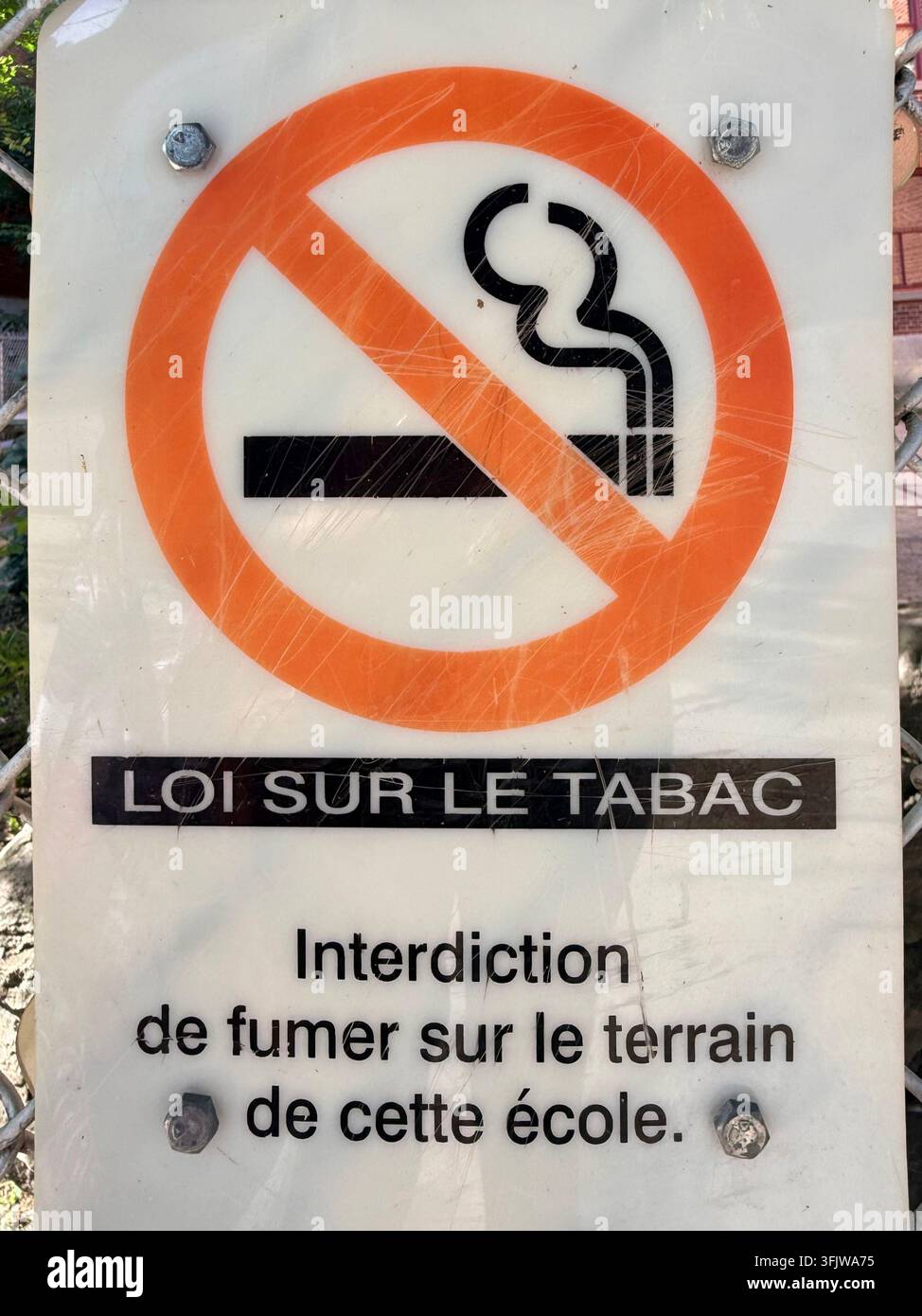 Panneau d'interdiction de fumer en langue française sur le terrain d'une école à Montréal, Québec, Canada, reflétant le contrôle du tabac et la réglementation de la santé publique - Image de stock capturée avec un smartphone