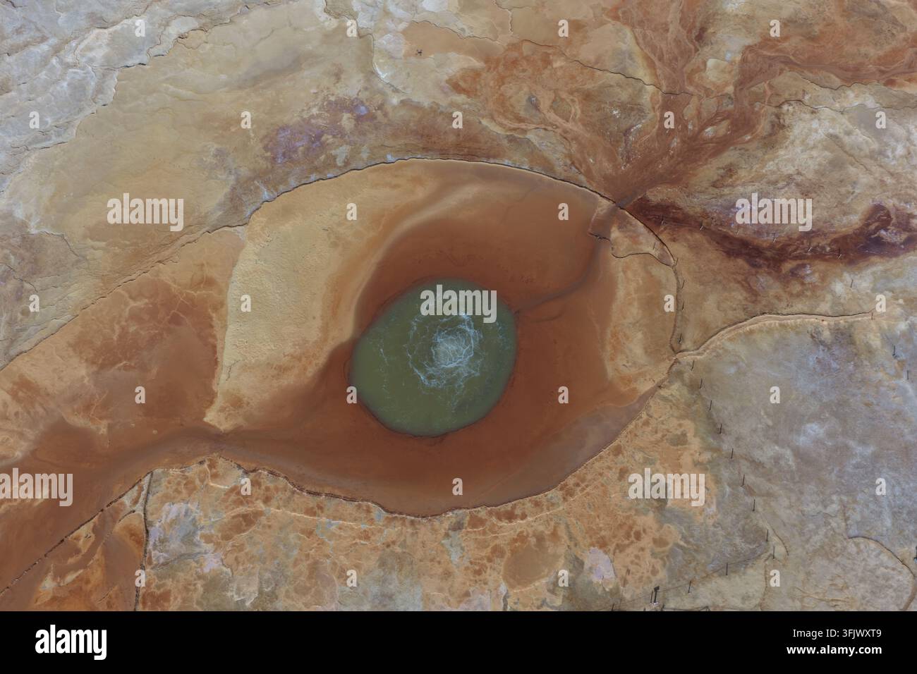 Une vue aérienne encadre l'œil minéral vert d'Aiken Spring au sein de cercles rouges et orange audacieux. Le motif surréaliste donne une impression d'un autre monde. Banque D'Images