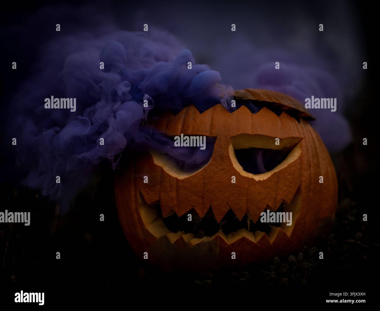 Citrouille d'Halloween sculptée avec un visage sinistre entourée d'une épaisse fumée violette sur un fond sombre, créant une atmosphère effrayante et dramatique. Banque D'Images