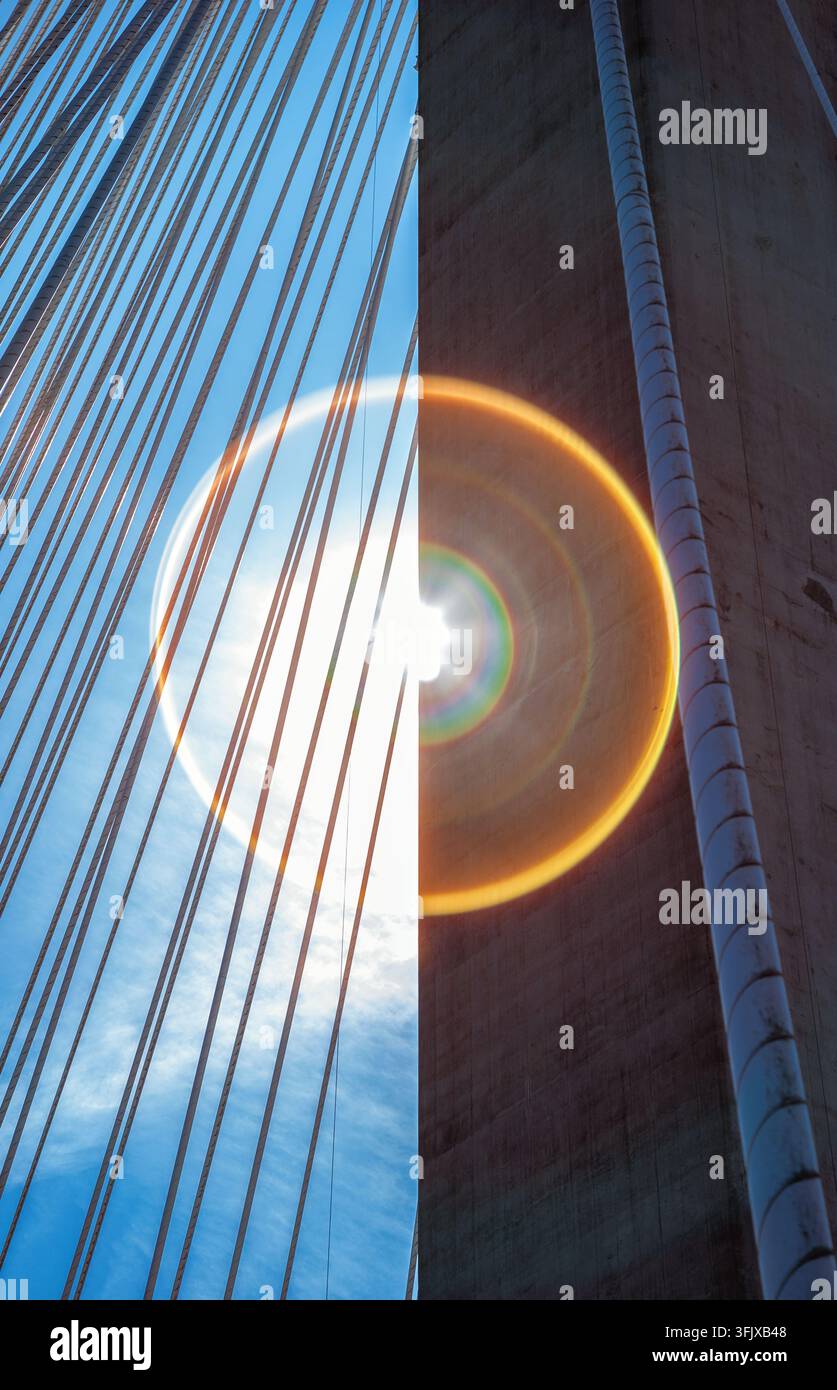 Abstrait vertical du pilier en béton du pont Port Mann et des câbles en acier divisés par un halo d'éclat de lumière arc-en-ciel circulaire à Surrey, en Colombie-Britannique. Banque D'Images
