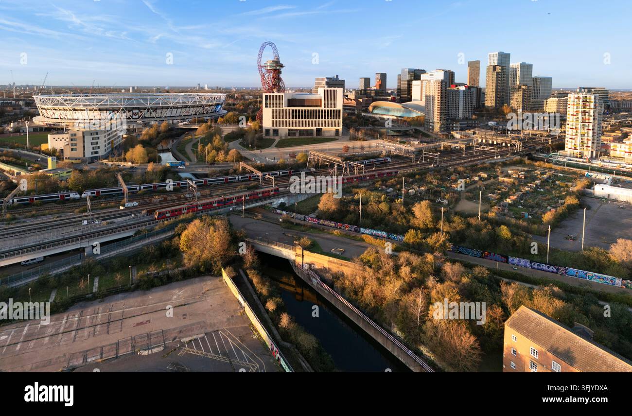 Des trains passent devant le London Stadium et la tour Orbit dans le Queen Elizabeth Olympic Park de Londres, illustrant les transports modernes et le développement urbain dynamique. Banque D'Images