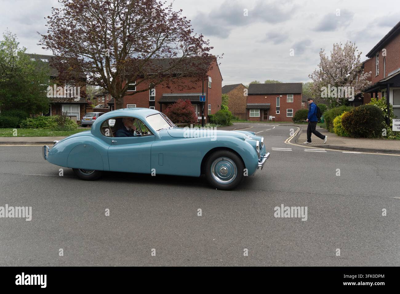 Un homme âgé conduit sa Jaguar XK120 bleue classique dans un quartier résidentiel à Londres, Royaume-Uni. Banque D'Images