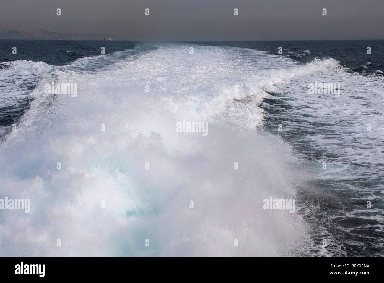 Bateau se déplaçant rapidement créant un sillage blanc mousseux sur l'eau bleue de l'océan pendant un voyage Banque D'Images