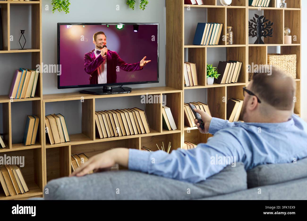 Homme en surpoids avec télécommande se détendant sur un canapé et regardant la télévision à la maison Banque D'Images