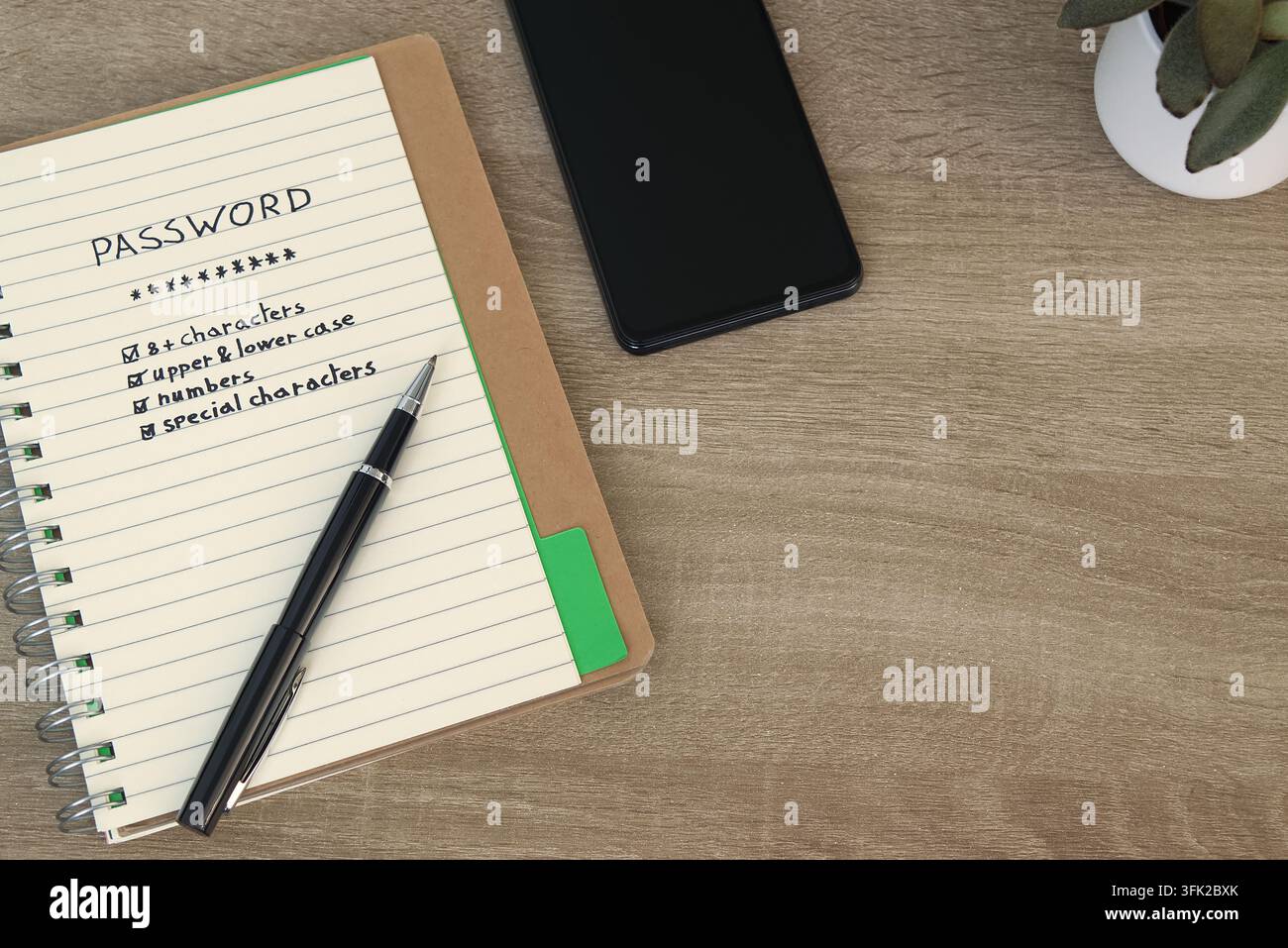 Page de cahier énumérant les exigences de sécurité des mots de passe — 8+ caractères, majuscules et minuscules, chiffres, caractères spéciaux — avec un stylo et un smartphone Banque D'Images