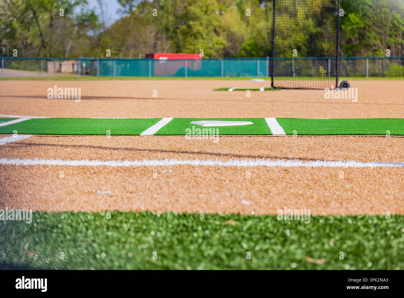 Une base blanche propre repose sur une parcelle de gazon vert marquant le diamant d'un terrain de baseball professionnel sous une lumière vive du jour. Banque D'Images