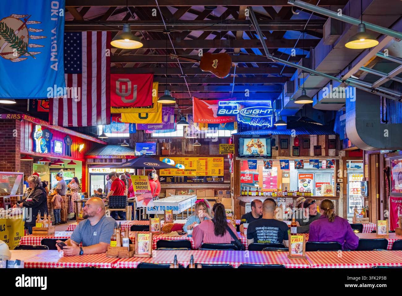 Oklahoma, États-Unis, 06 AVR 2024 – Les clients se détendent à des tables à carreaux rouges dans une taverne animée décorée de drapeaux, de souvenirs sportifs et Banque D'Images