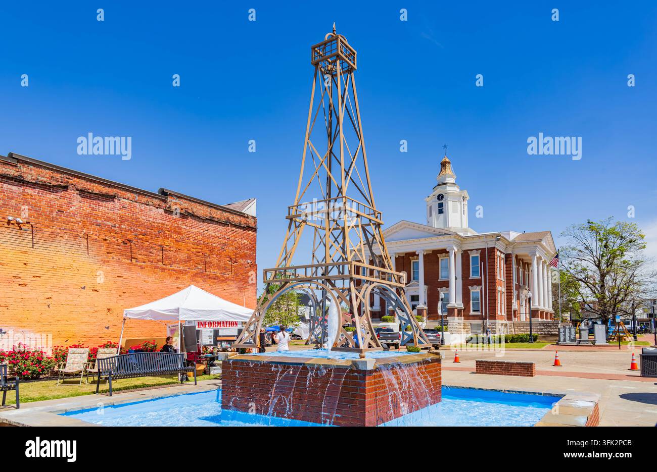 Arkansas, États-Unis, 07 AVR 2024 - L'eau jaillit d'une base de fontaine en brique sous une structure métallique imposante dans une place urbaine lumineuse. Banque D'Images