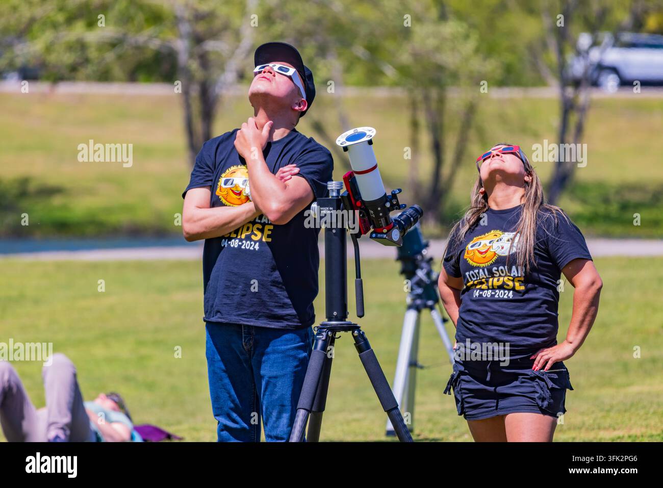 Arkansas, États-Unis, 08 AVR 2024 – Un homme et une femme se tiennent dans un champ herbeux à côté d’un télescope tout en regardant le ciel lors d’une éclipse solaire Banque D'Images
