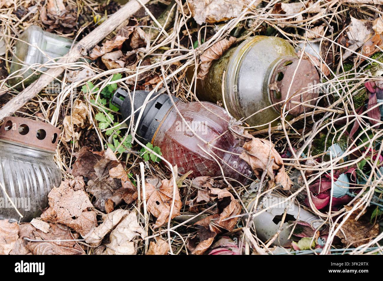 Bouteilles en verre et canettes abandonnées parmi des feuilles sèches en plein air. Fond de pollution pour déchets de litter, dommages environnementaux et déversement illégal. Banque D'Images